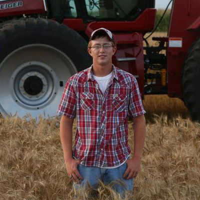 Portrait of Kyle Nelson in front of a farm tractor