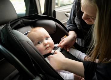 Infant being buckled into their car seat