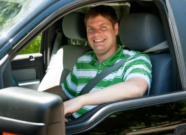 Driver wearing a seatbelt smiling at the camera