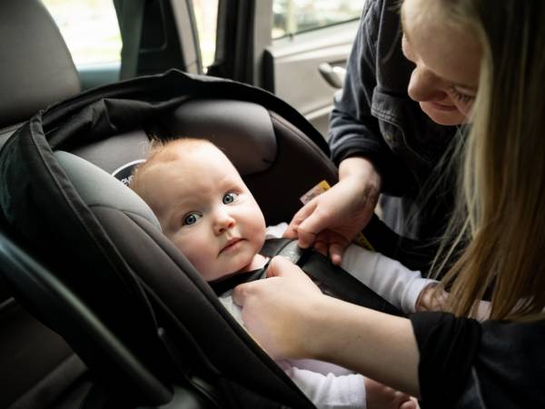 Infant being buckled into their car seat